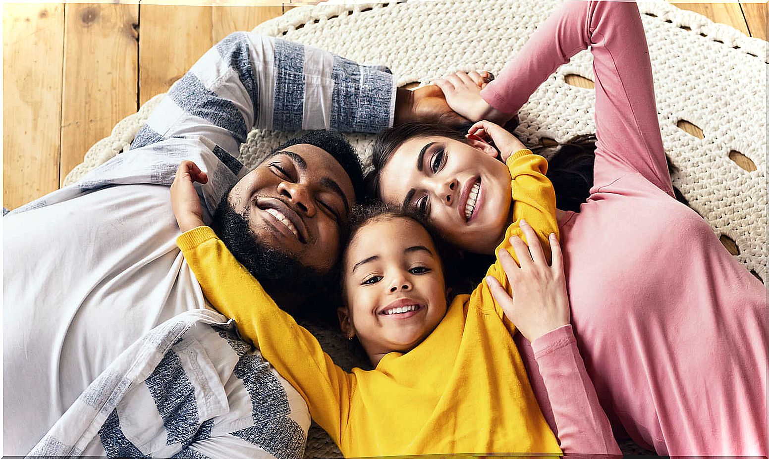 Happy family lying on the floor as they hug each other to practice connected parenting.