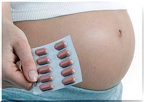 Pregnant woman holding folic acid pills