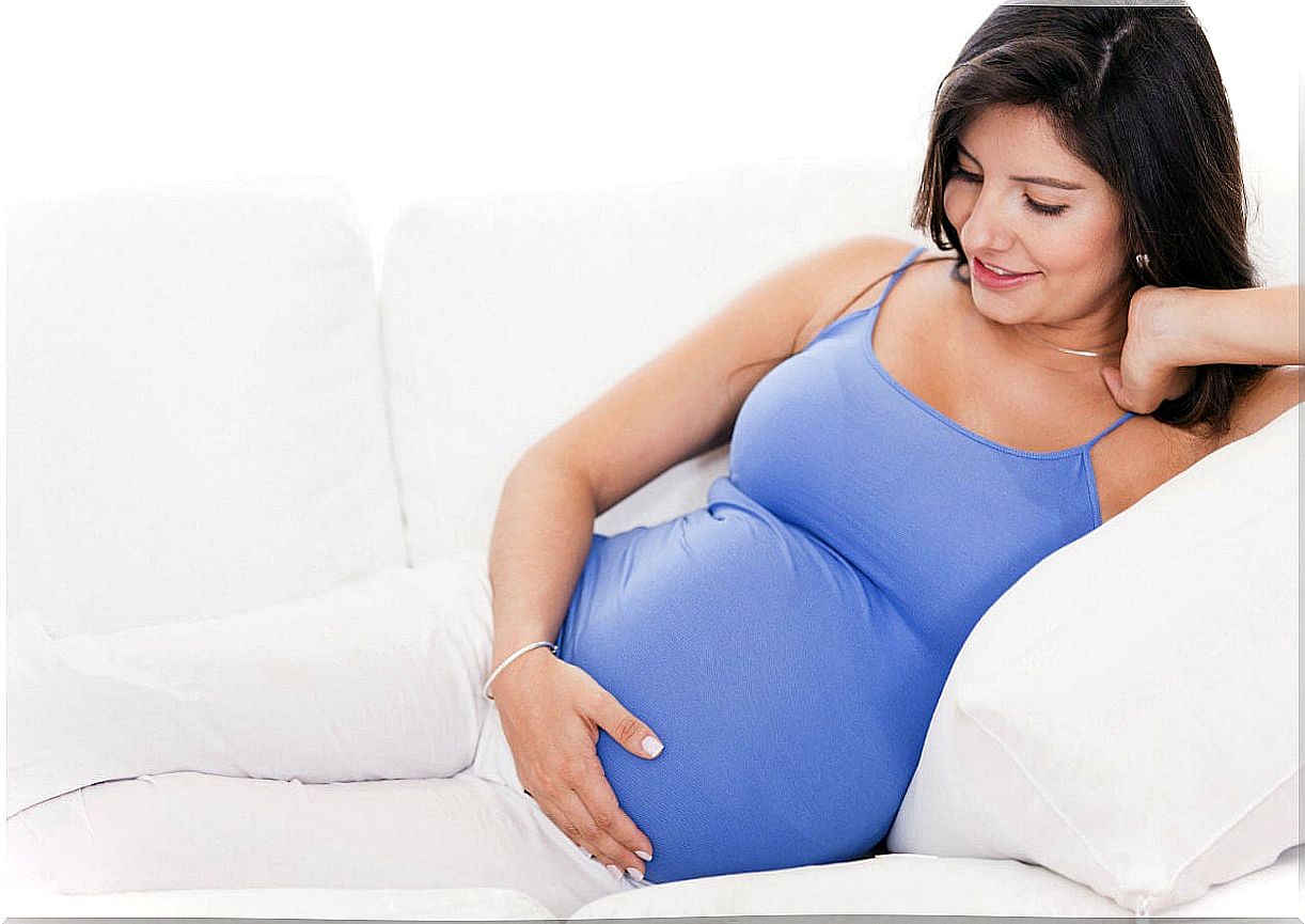 Pregnant woman clutching her gut and smiling