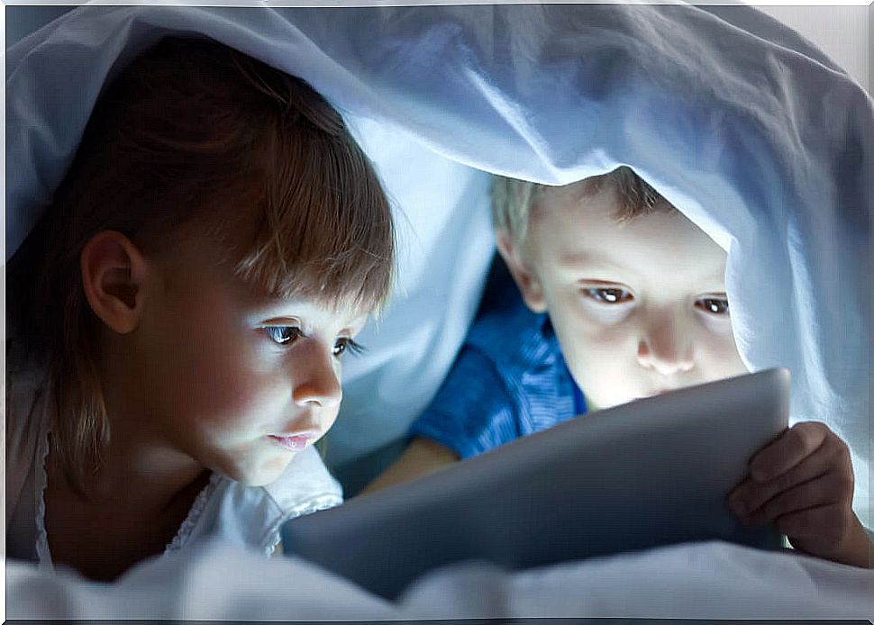 Children watching a movie under the covers on a gadget such as the tablet.