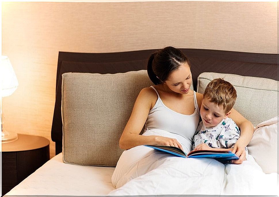 Mother reading a story to her son in bed to introduce him to the world of reading.