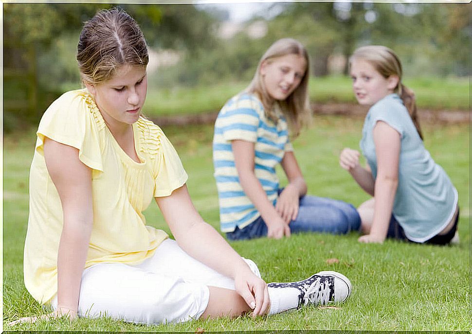 Girl sitting alone on the grass because she has no friends.