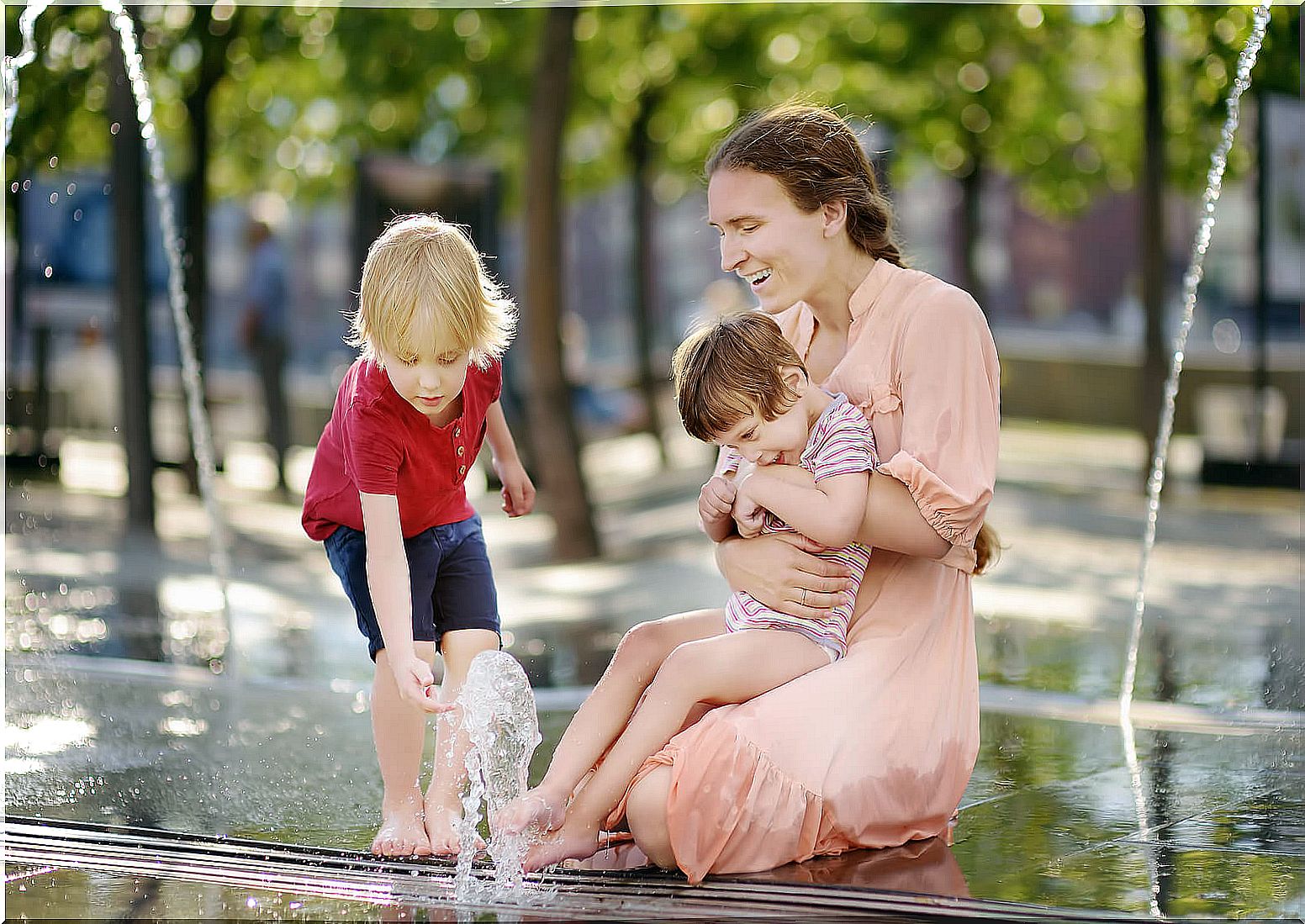Mother playing with her children next to a fountain.